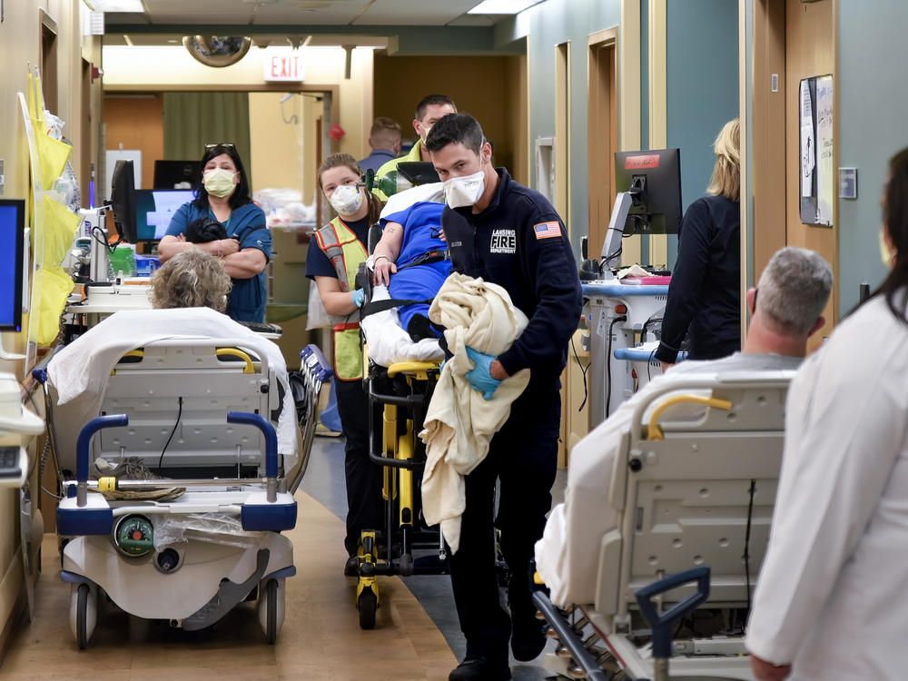 An ambulance crew weaves a gurney through the halls of Sparrow Hospital's emergency department in Lansing, Michigan. Overcrowding has forced the staff to triage patients, putting some in the waiting rooms and treating others on stretchers and chairs in the halls.