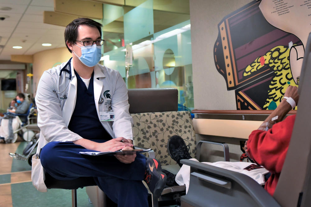 A student from the College of Osteopathic Medicine at Michigan State University consults with a patient in the hallway of Sparrow Hospital's ER.