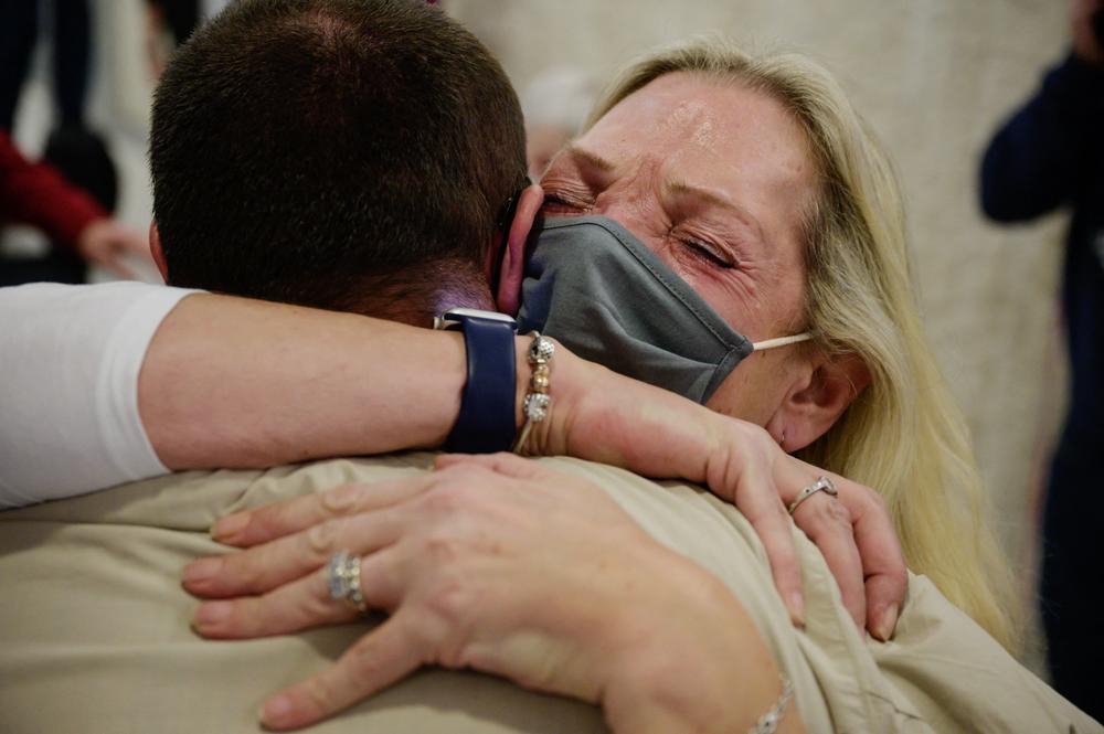 Alison Henry embraces her son Liam as they meet after arriving on a flight from the UK.