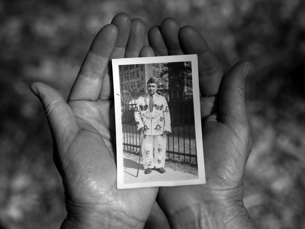 Sheridan MacKnight holds a photograph of her grandfather John B. McGillis. In the photograph, McGillis wears a hand-made beaded buckskin suit and a U.S. army cap from his service in WWI.