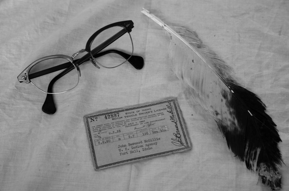 Items MacKnight's great grandfather collected in his trunk: an Idaho driver's license, horn-rimmed glasses, and an eagle feather.