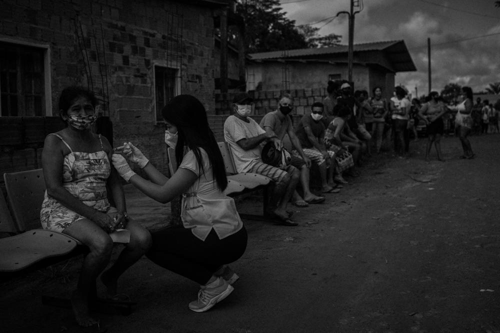 A nursing technician administers doses of COVID-19 vaccine to residents of São Sebastião da Serra Baixa, a rural community located in Iranduba, Amazonas, Brazil, on April 15, 2021. In the second wave of the disease, the city had a curfew to avoid an increase in cases.