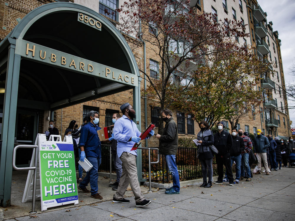 People line up outside a free COVID-19 vaccination site that opened Friday in Washington, D.C. The local health department is stepping up vaccination and booster shots as more cases of the omicron variant are being identified in the United States.