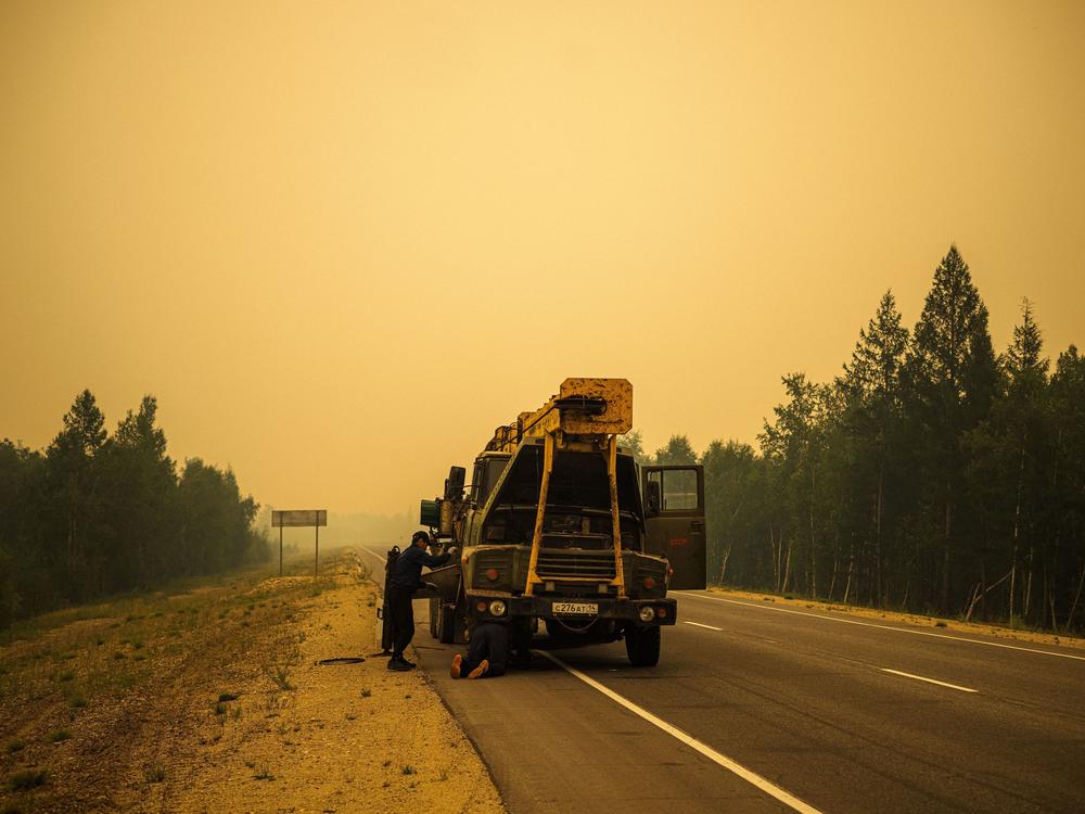Men repair their truck in smoke from a forest fire on a road near Magaras, in the republic of Sakha, Siberia, in July.