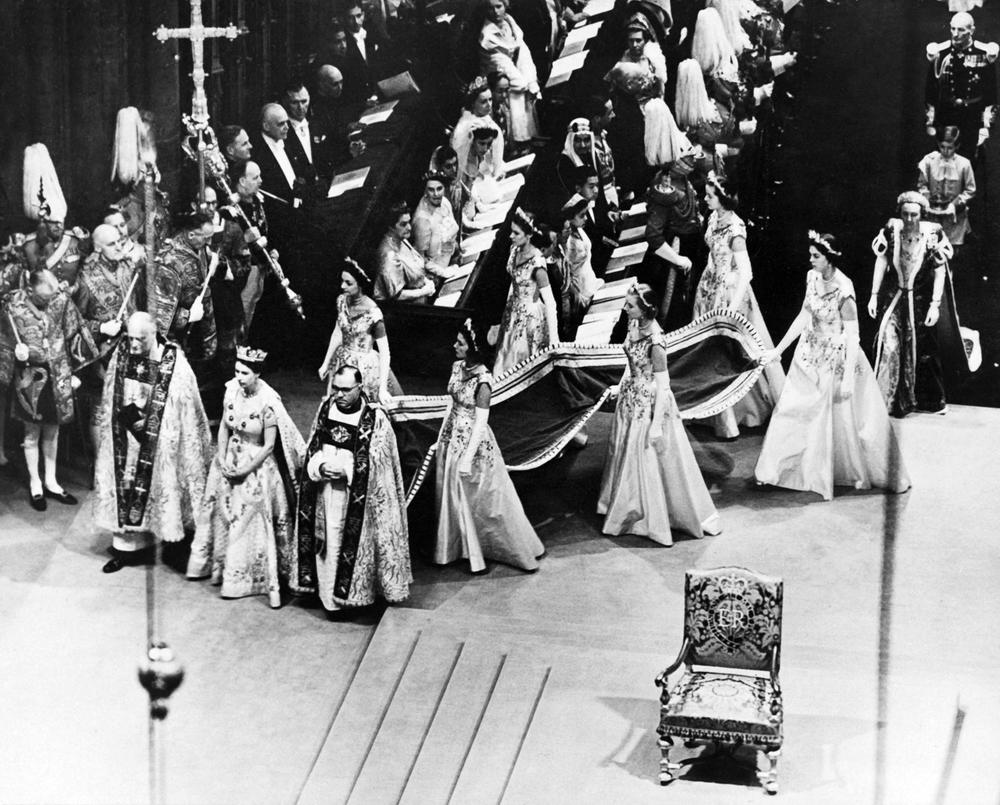 <strong>June 2, 1953:</strong> Queen Elizabeth II, surrounded by the bishop of Durham Lord Michael Ramsay (left) and the bishop of Bath and Wells Lord Harold Bradfield, walks to the altar during her coronation ceremony in Westminster Abbey, London, as her maids of honor carry her train.