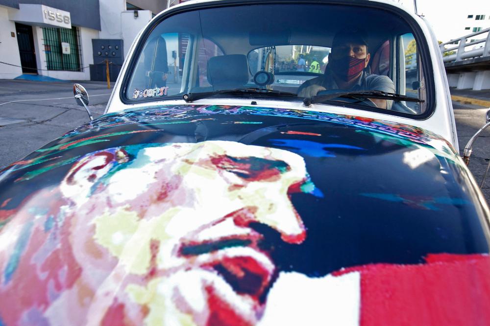 A fan of Mexican singer Vicente Fernández arrives in a car with his portrait outside the Country 2000 hospital where he died, in Guadalajara, Mexico, on Dec. 12.