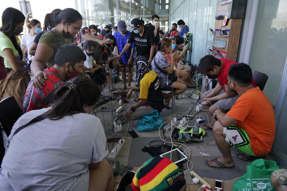 Residents line up to charge their phones for free at a mall after Typhoon Rai damaged power lines and other parts of Cebu city, central Philippines on Saturday, Dec. 18, 2021.