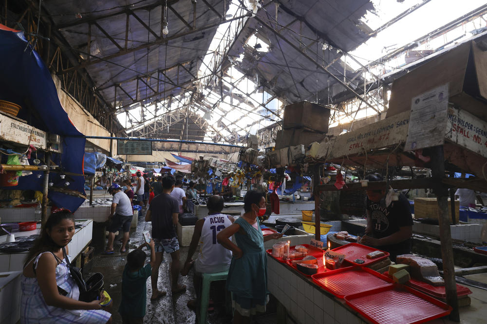 In this photo provided by Greenpeace, residents buy at a damaged public market due to Typhoon Rai in Surigao city, Surigao del Norte, southern Philippines on Sunday Dec. 19, 2021.
