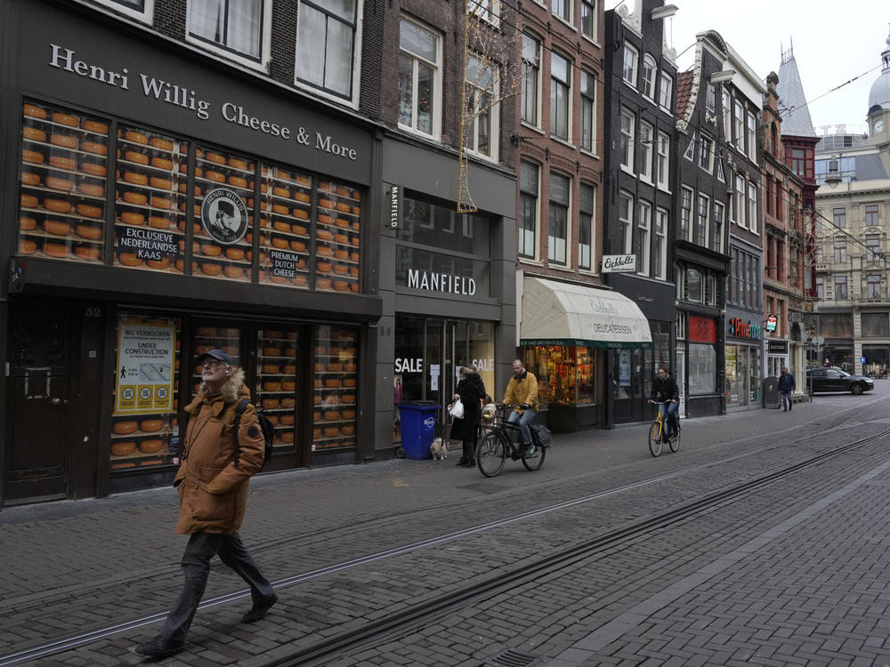 A handful of people traverse down a normally bustling shopping street in the center of Amsterdam on Monday. Nations across Europe have reimposed tougher measures to stem a new wave of coronavirus infections spurred by the highly transmissible omicron variant. The Netherlands has imposed a nationwide lockdown.
