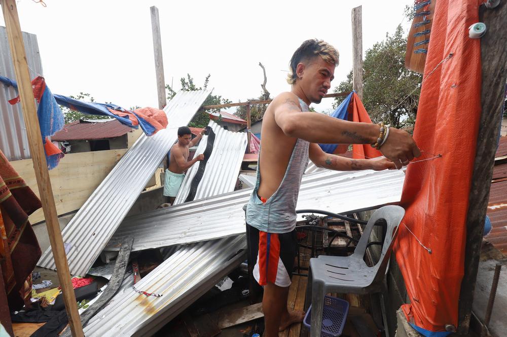 Residents repair the roof of their collapsed house in Iloilo city on December 17, 2021, a day after Super Typhoon Rai pummelled the southern and central regions of the Philippines.