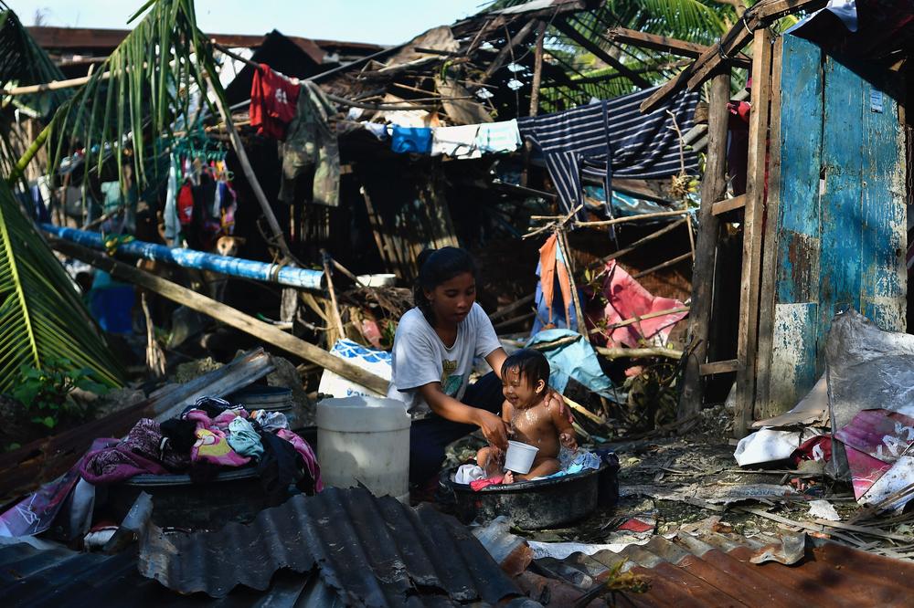 A resident bathes her child next to their destroyed house in Carcar, Philippines' Cebu province on December 18, 2021, days after Super Typhoon Rai hit the city.