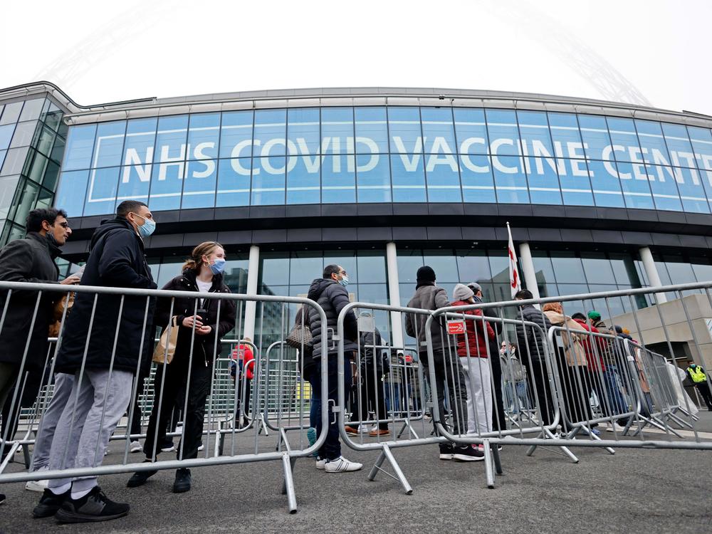 People queue outside the newly set up vaccination center at London's Wembley Stadium to receive a COVID-19 vaccine or booster on Sunday, as the booster rollout accelerates in England and case numbers spike.