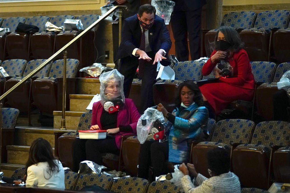 Rep. Jason Crow, D-Colo., directs fellow members of Congress to put on their plastic smoke-hood respirators as they are evacuated from the House chamber as protesters attempt to enter on Jan. 6, 2021.