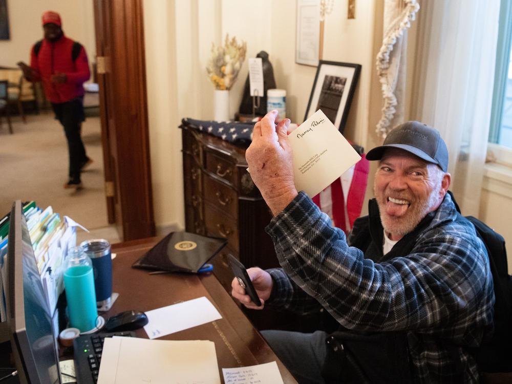 Richard Barnett, a supporter of then-President Donald Trump, holds a piece of mail as he sits in House Speaker Nancy Pelosi's office after protesters breached the Capitol on Jan. 6, 2021.