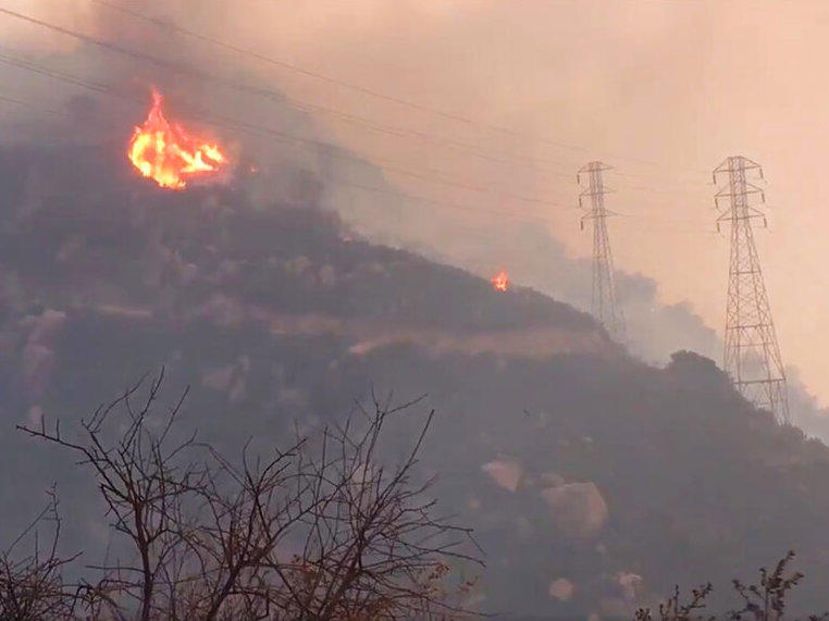 FILE - In this Saturday, Dec. 16, 2017, file image taken from video provided by the Santa Barbara County Fire Department, spot fires burn near power lines as heavy smoke fills the air from a wildfire in Santa Barbara, Calif.