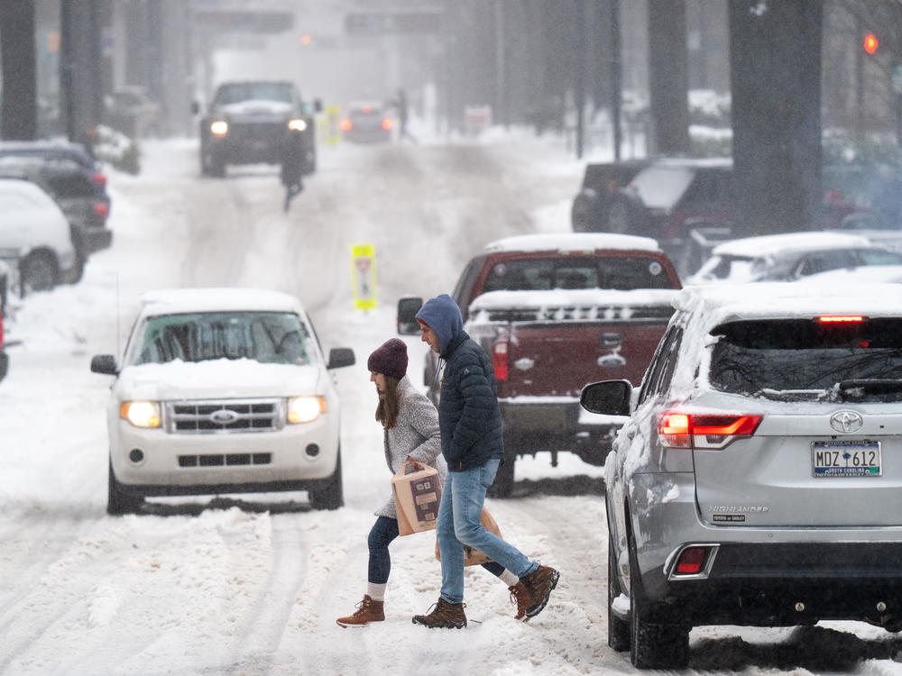 Pedestrians cross a street as motorists drive through the snow on Jan. 16 in Greenville, S.C.