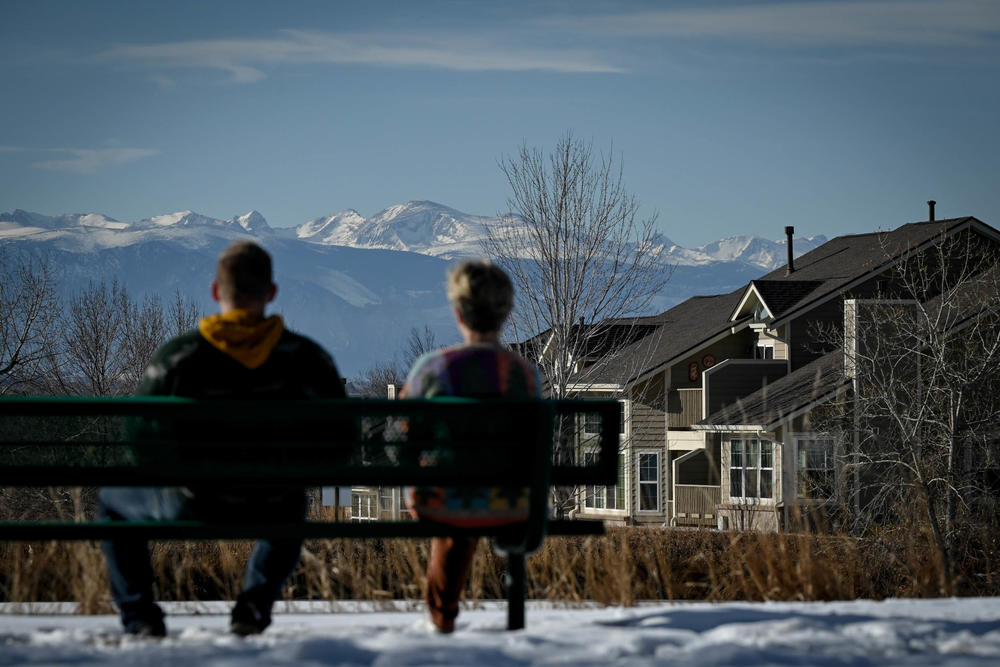 Two people sit in the foreground as Colorado's Rocky Mountains stand tall in the distance of Westminster, Colo., on Jan. 29.
