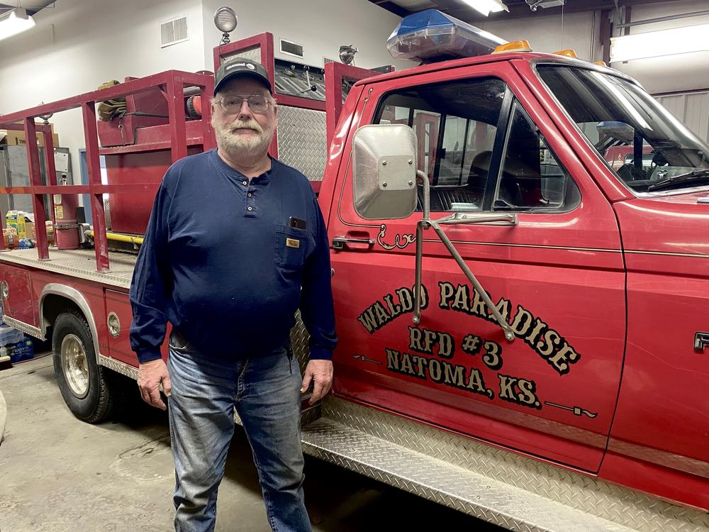 Keith Koelling is 62 and still fighting fires. He says he worked 40 hours straight on a recent fire, only to find out he had COVID-19 at the time. He's standing next to a 26-year-old fire truck.