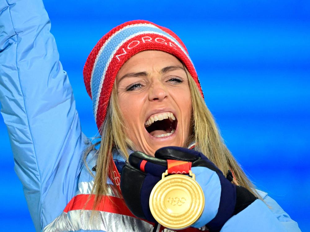 Medallist Norway's Therese Johaug, the first person to win gold at the Beijing Winter Olympics, celebrates on the podium during the women's skiathlon victory ceremony.