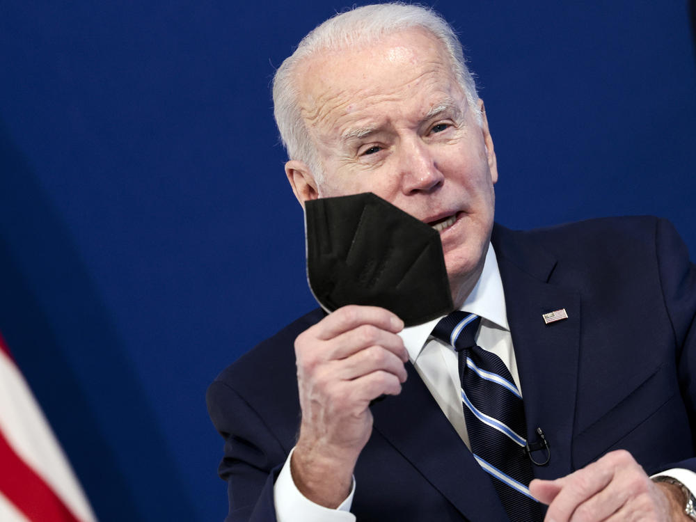 Joe Biden holds a mask as he gives remarks on his administration's response to the surge in COVID-19 cases across on January 13, 2022.