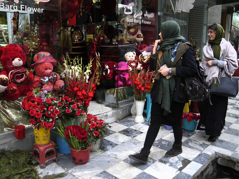 Afghan women pass a flower shop decorated for Valentine's Day in Kabul, Afghanistan, Sunday, Feb. 13, 2022.