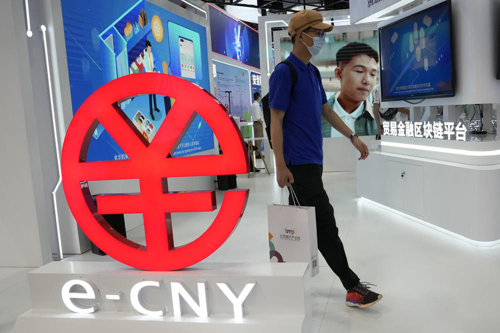 A visitor passes by a logo for the e-CNY, a digital version of the Chinese yuan, displayed during a trade fair in Beijing, last September. That same month, China's central bank declared all transactions involving Bitcoin and other virtual currencies illegal, stepping up a campaign to block use of unofficial digital money.