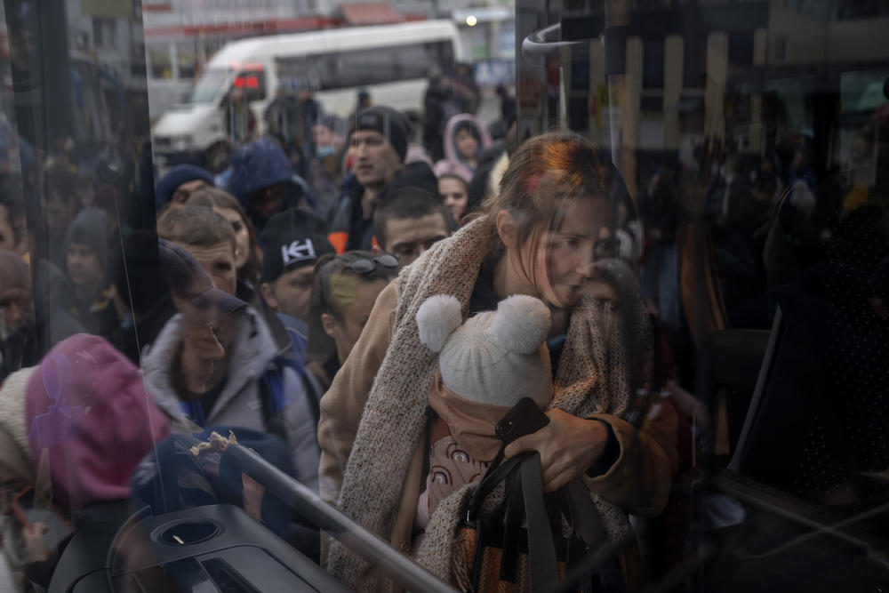 A woman holds her baby as she gets on a bus leaving Kyiv on Feb. 24.