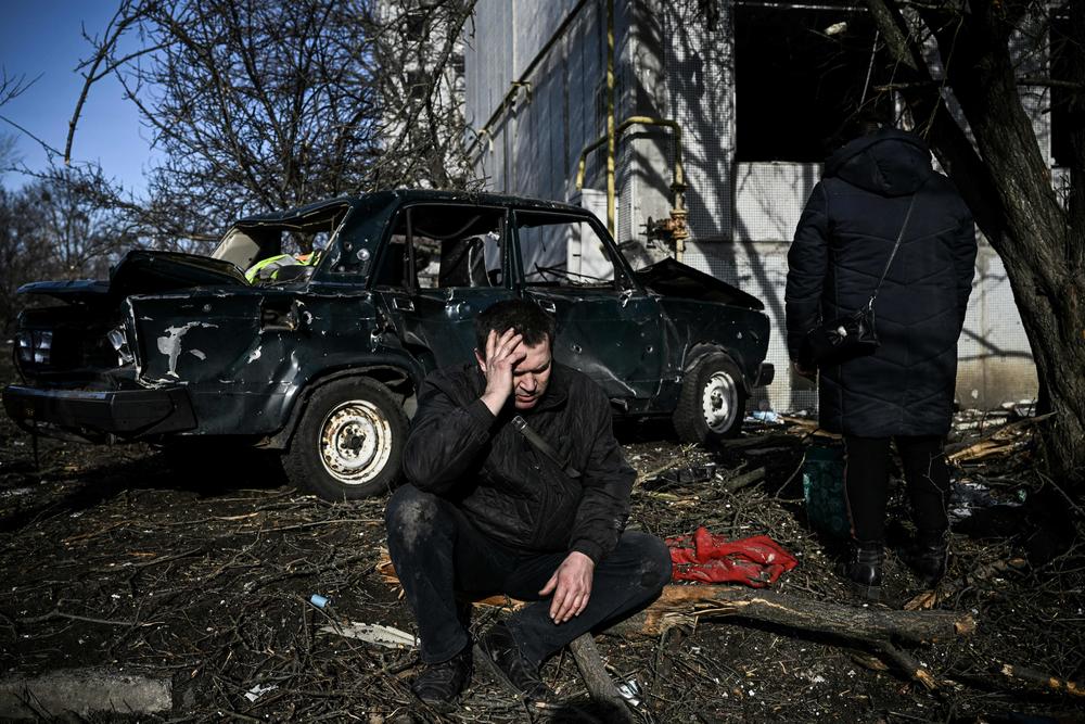 A man sits outside his destroyed building after bombings on the eastern Ukrainian town of Chuhuiv on Feb. 24, as Russian armed forces are trying to invade Ukraine from several directions, using rocket systems and helicopters to attack Ukrainian positions in the south, the border guard service said.