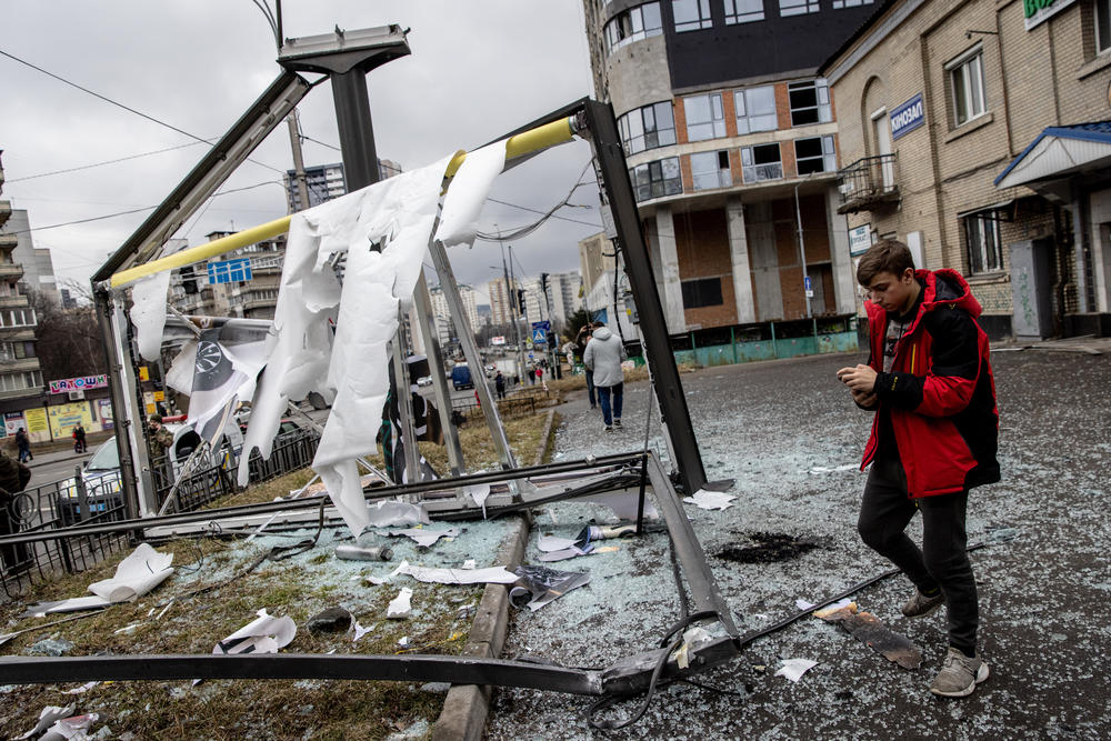 A person walks by a structure that was damaged by a rocket on Feb. 24 in Kyiv.