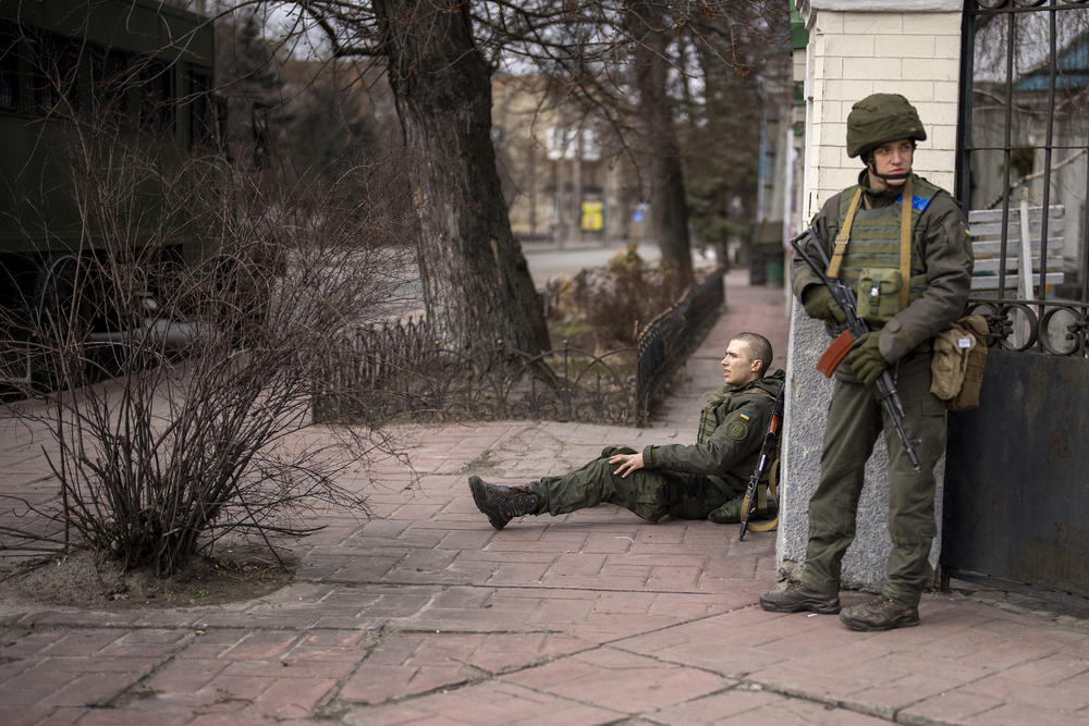A Ukrainian soldier sits injured in cross fire inside the city of Kyiv, Ukraine, Friday, Feb. 25, 2022. Russia pressed its invasion of Ukraine to the outskirts of the capital Friday after unleashing airstrikes on cities and military bases and sending in troops and tanks from three sides in an attack that could rewrite the global post-Cold War security order.