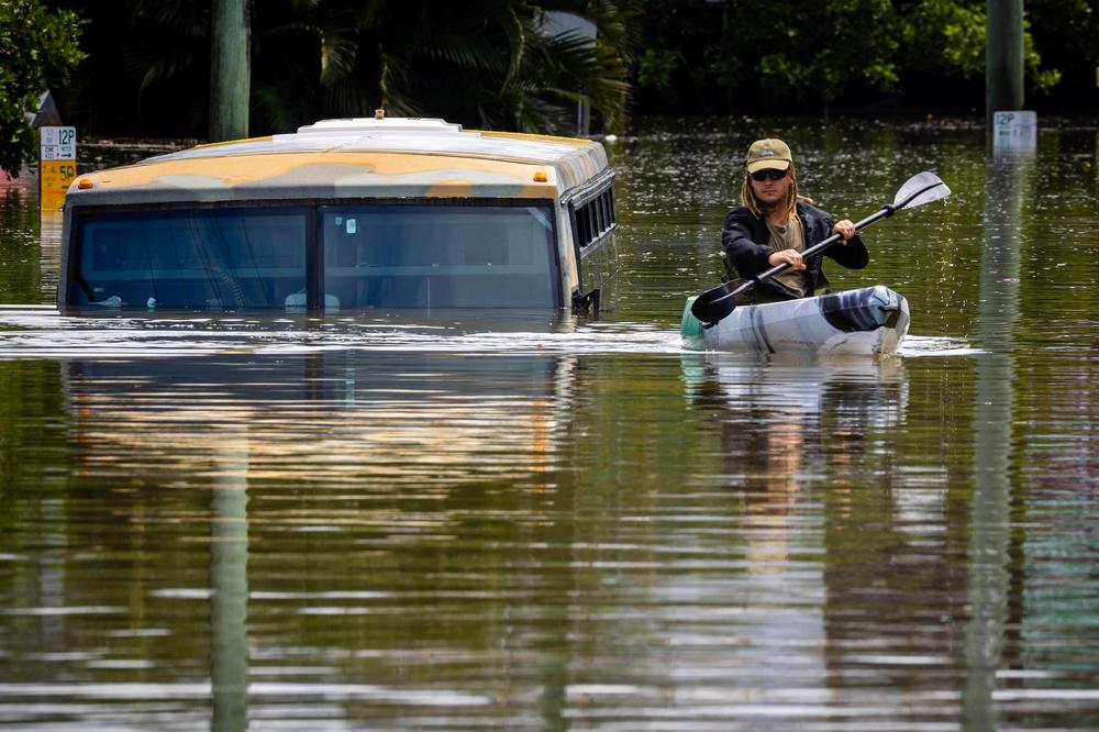A man paddles his kayak next to a submerged bus on a flooded street in the town of Milton in suburban Brisbane, Australia, on Monday.