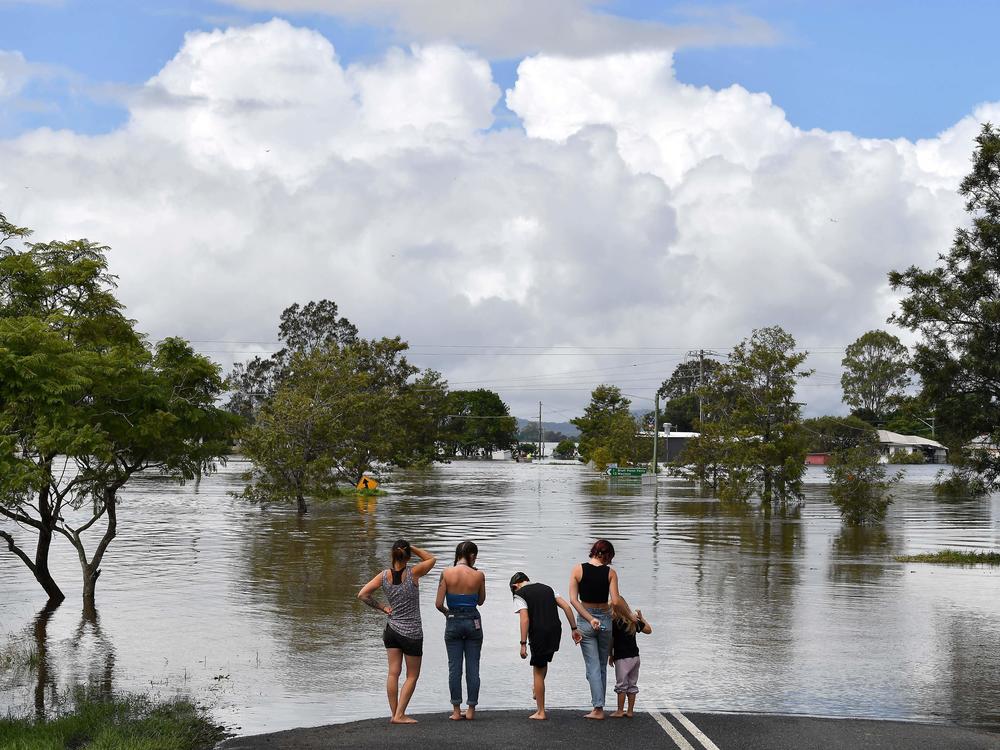 A family stays next to a flooded street in Lawrence, Australia, some 45 miles from the New South Wales town of Lismore, on Tuesday.