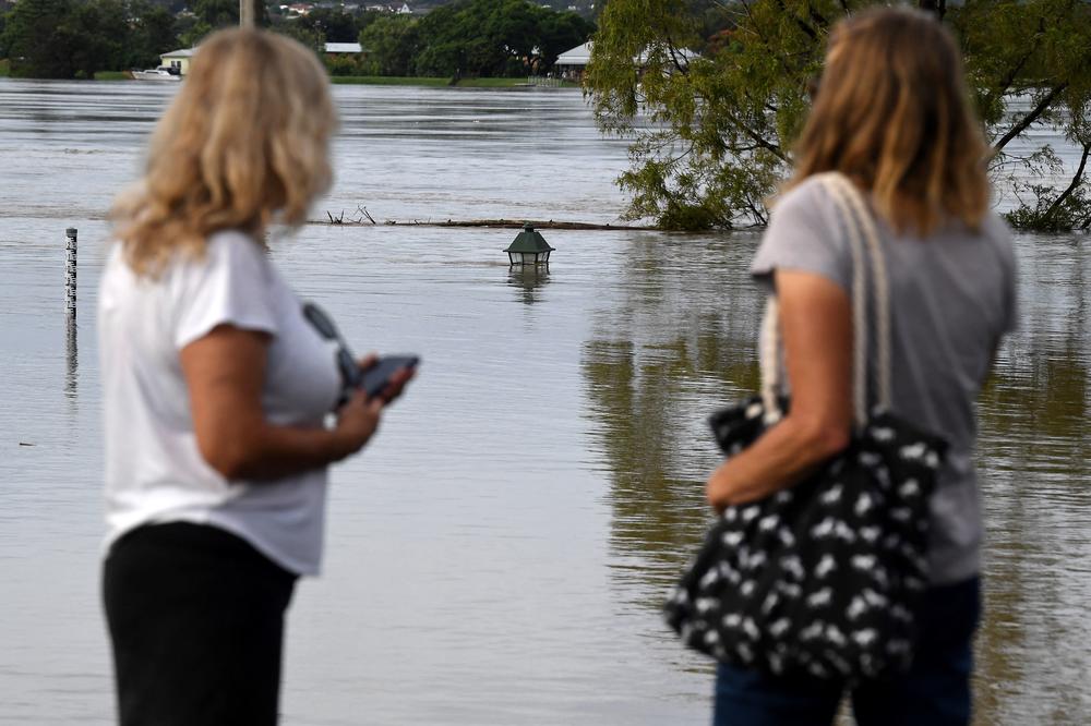 A family looks at a nearly submerged lamp post from the banks of the overflowing Clarence River in Grafton, Australia, some 80 miles from the New South Wales town of Lismore, on Tuesday.