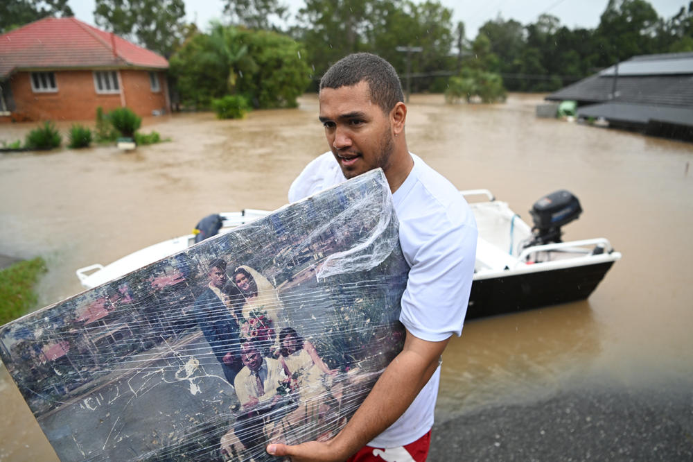 A man carries a wedding photo as people evacuate homes inundated by floodwaters Sunday in Goodna, Australia.