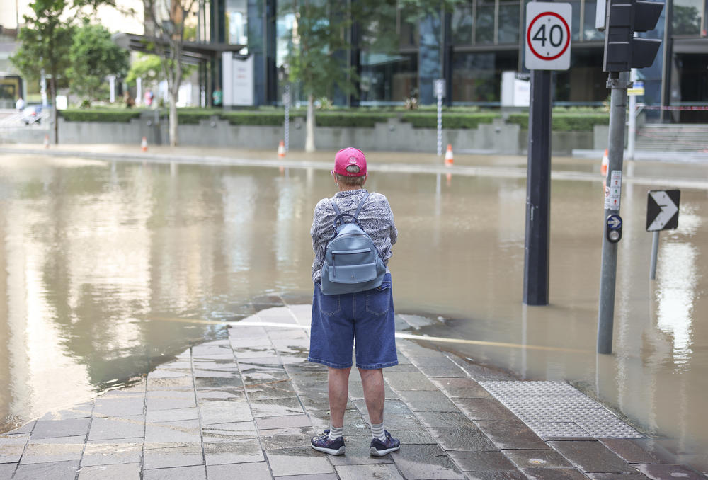 A local watches the floodwaters in Brisbane, Australia's central business district Monday.