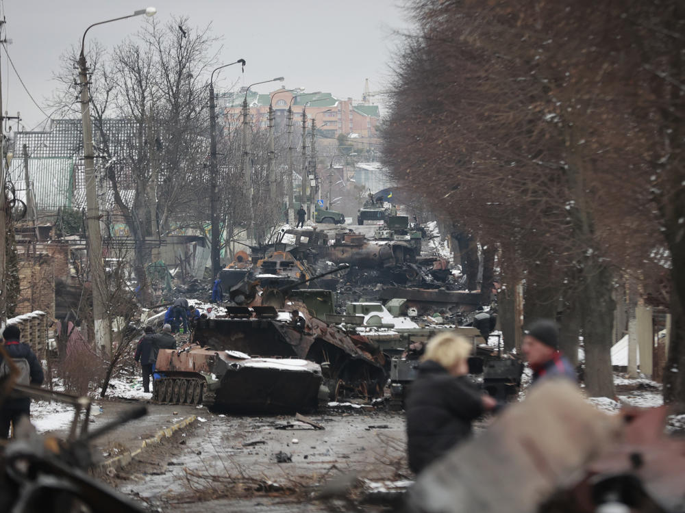 People look at the gutted remains of Russian military vehicles on a road in the town of Bucha, close to the capital Kyiv, on Tuesday.