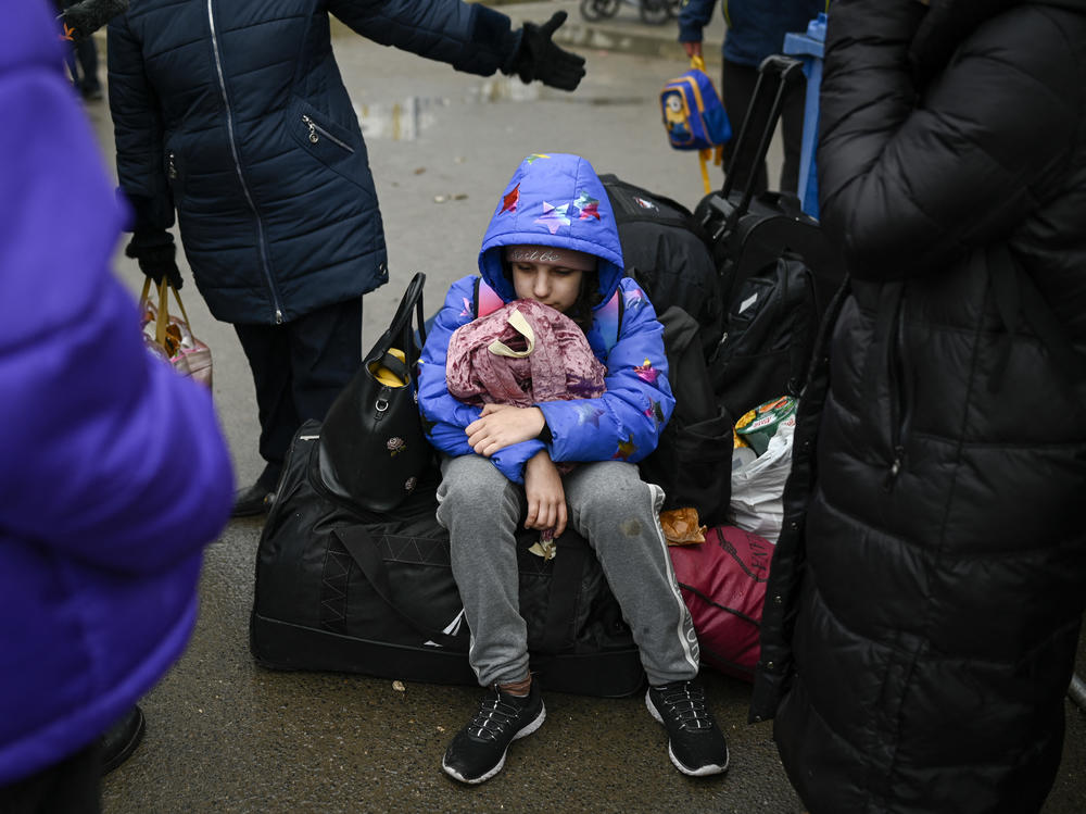 A child fleeing the conflict in Ukraine rests on a suitcase after crossing the Moldova-Ukraine border checkpoint near the town of Palanca on Wednesday, seven days after Russia's invasion of Ukraine.
