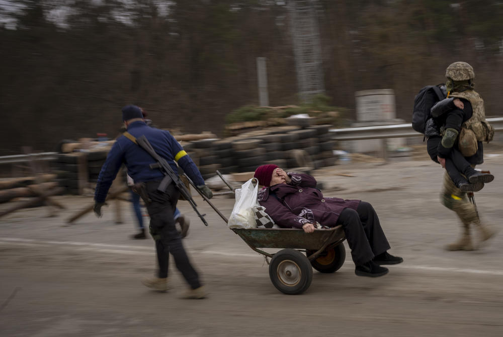 <strong>March 5:</strong> A Ukrainian soldier and a militia man help a fleeing family crossing the Irpin river in the outskirts of Kyiv, Ukraine.