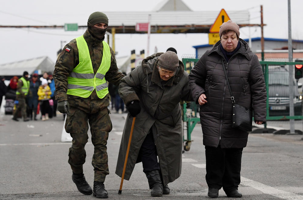 A Polish soldier helps elderly people coming from Ukraine, as they cross the Ukrainian-Polish border in Korczowa, Poland.