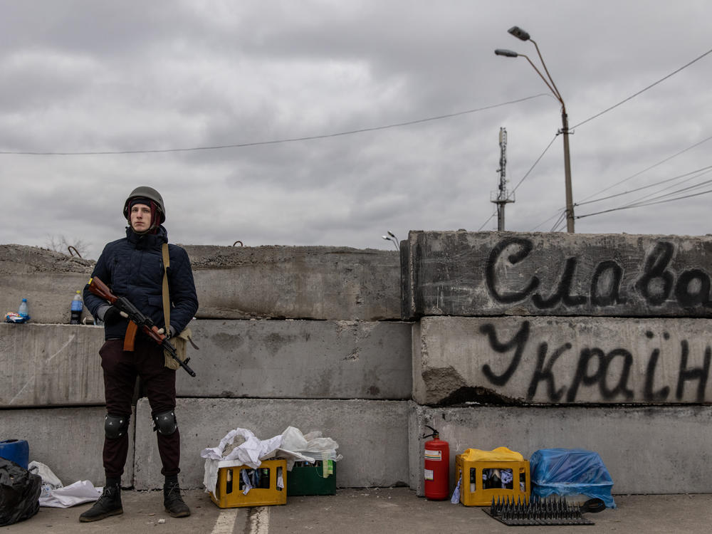 A member of a Territorial Defense unit guards a barricade next to writing saying 