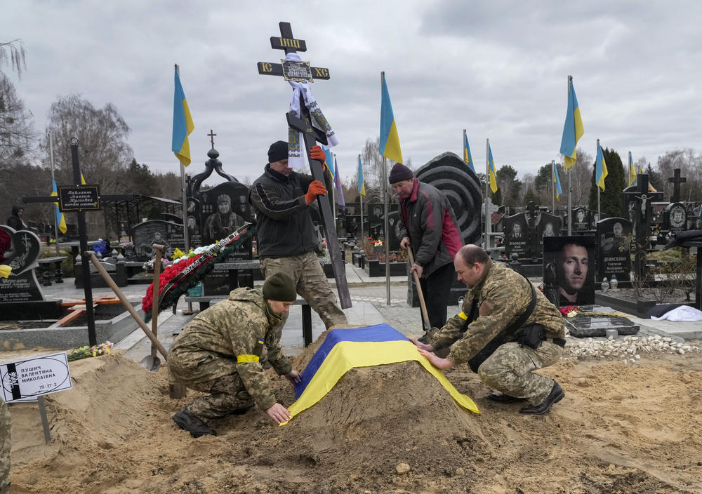 <strong>March 5:</strong> Ukrainian paramedics cover with the National flag the grave of their colleague Valentyna Pushych killed by Russian troops in a cemetery in Kyiv, Ukraine.