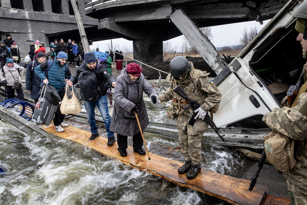 Residents flee heavy fighting via a destroyed bridge as Russian forces entered Irpin, Ukraine, on Monday.
