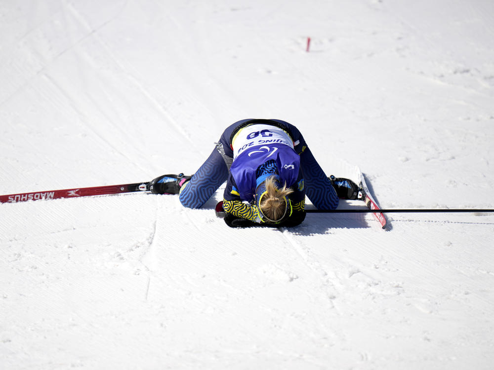 Ukraine's Oleksandra Kononova collapses after crossing the finish line and earning silver in the women's biathlon middle distance standing event on Tuesday.
