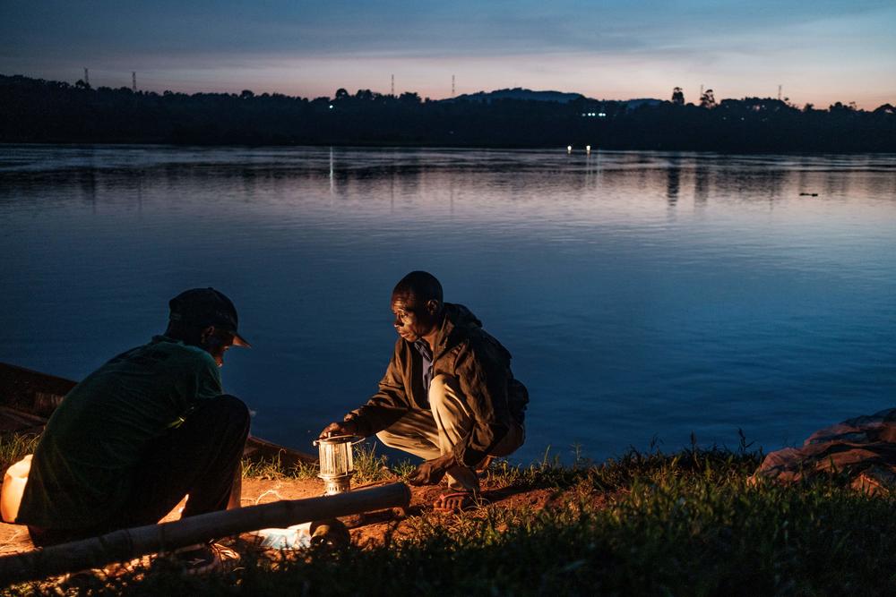 Jombi, left, and Mukasa, right, prepare kerosene lamps which will be used to attract the silverfish at night on the Nile river in Bujagali, Uganda, on Nov. 12, 2020. Fishermen in Uganda using more traditional fishing methods have been struggling to financially sustain themselves due to the lack of clients, which was caused by lockdowns imposed to curb the spread of COVID-19 coronavirus.