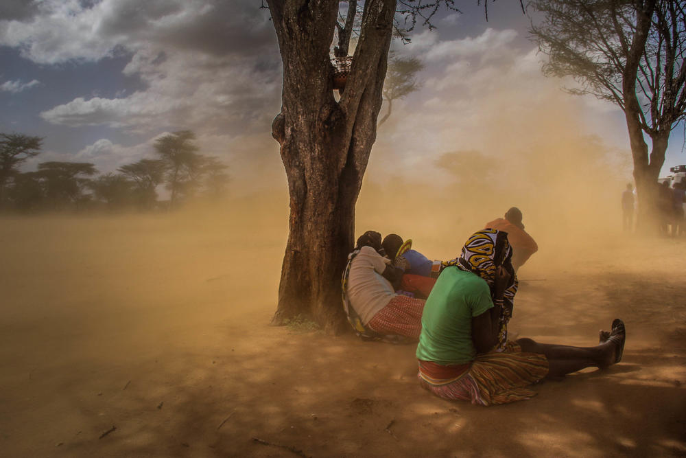 People look for cover when these dusty gushes of wind happen, Karamoja, Uganda, Feb. 2017. Photographer, Sumy Sadurni, travelled to Northern Uganda to capture how the Karamajong tribe live. The nomadic tribe are famous for their elaborate scar patterns, athletic prowess and beautiful woman, but Sumy wanted to focus on how the climate change has affected their lives in a big way.