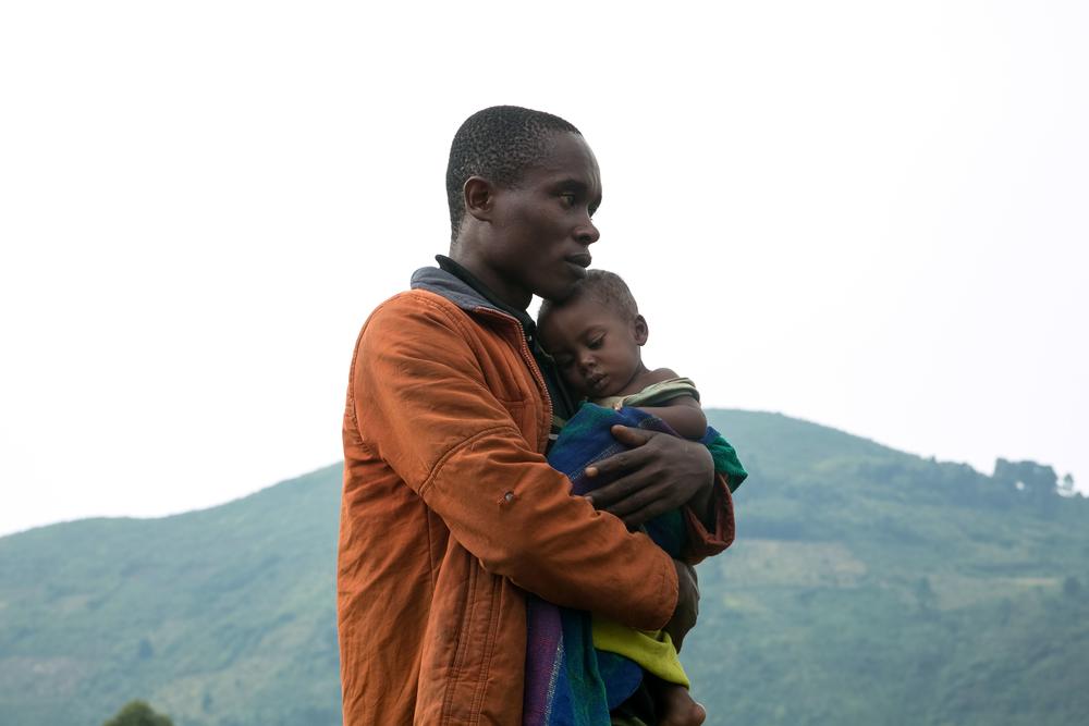 A Congolese man holds his child after he crossed the border from the Democratic Republic of Congo (DRC) to be refugees at Nteko village in western Uganda on Jan. 24, 2018.