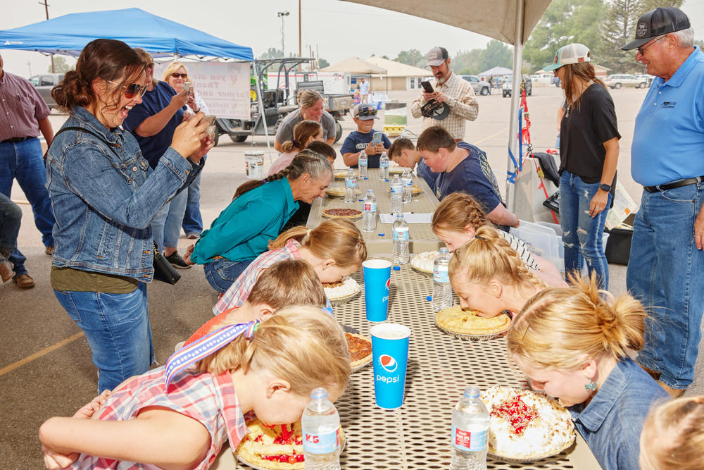 A crowd looks on competitors participate in the Moffat County Fair's pie-eating contest in Craig, Colo., on Aug. 7, 2021.