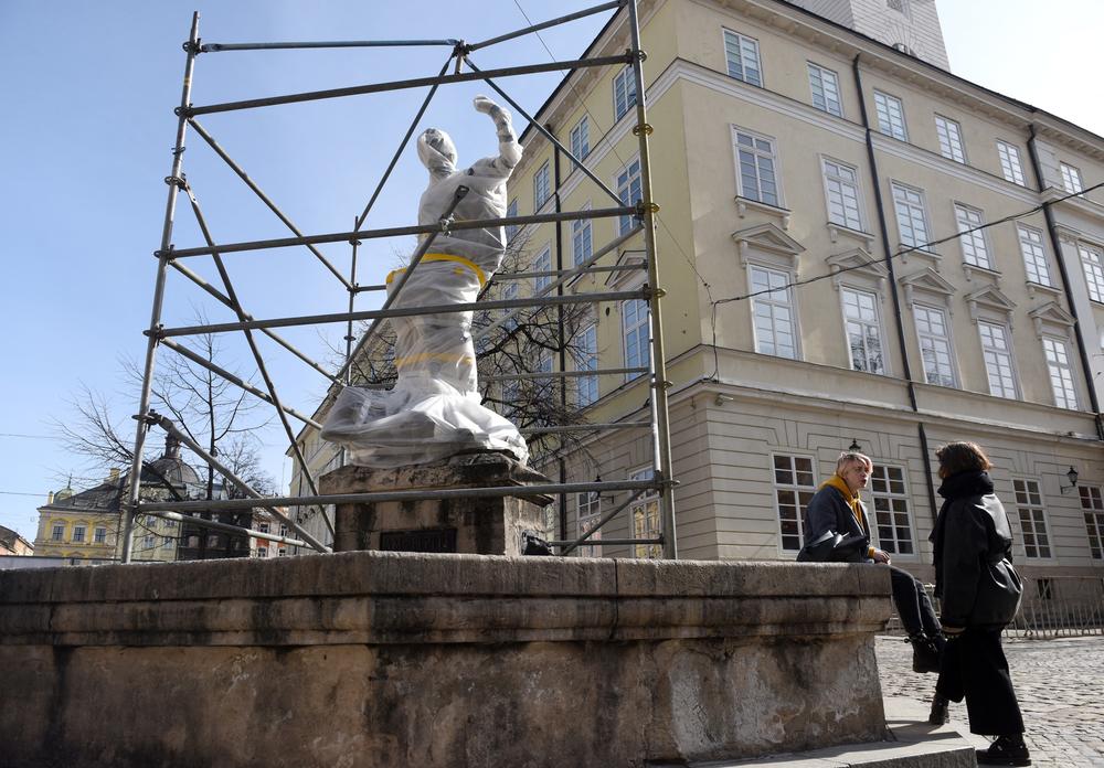 <strong>March 12:</strong> People talk near the wrapped statue of Diana, sitting atop a fountain, near the city council in Lviv, western Ukraine.