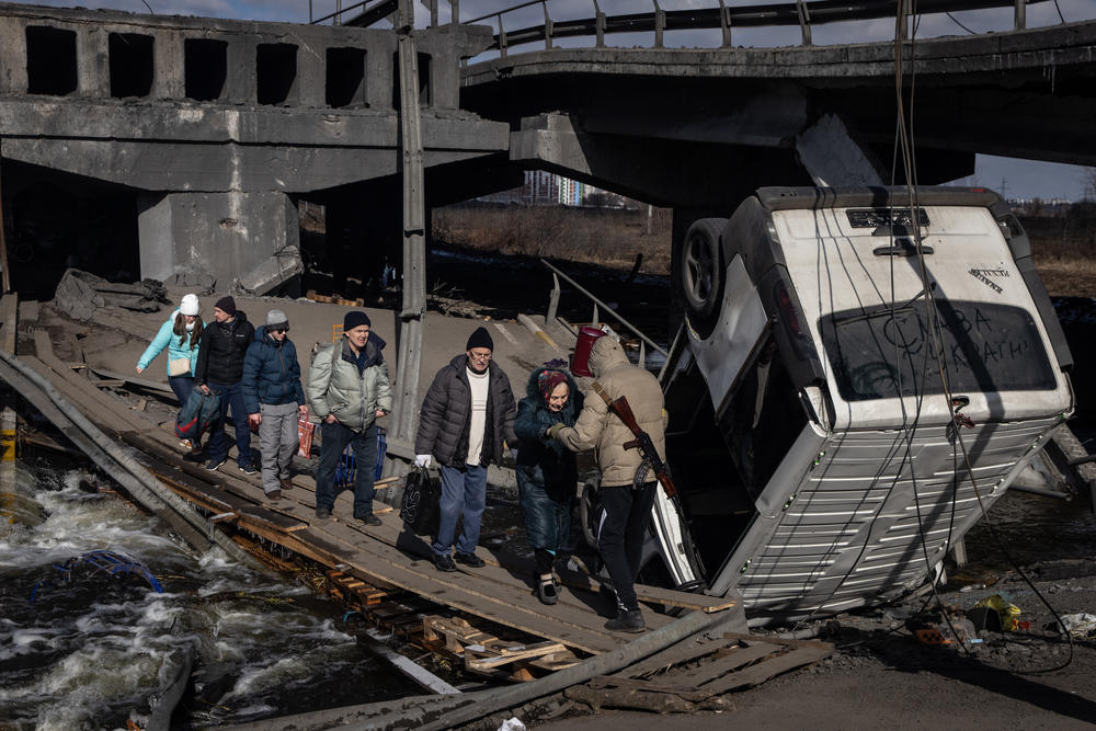 <strong>March 10:</strong> Residents of Irpin and Bucha flee fighting via a destroyed bridge in Irpin, Ukraine. Irpin, a suburb northwest of Kyiv, had experienced days of sustained shelling by Russian forces advancing toward the capital.
