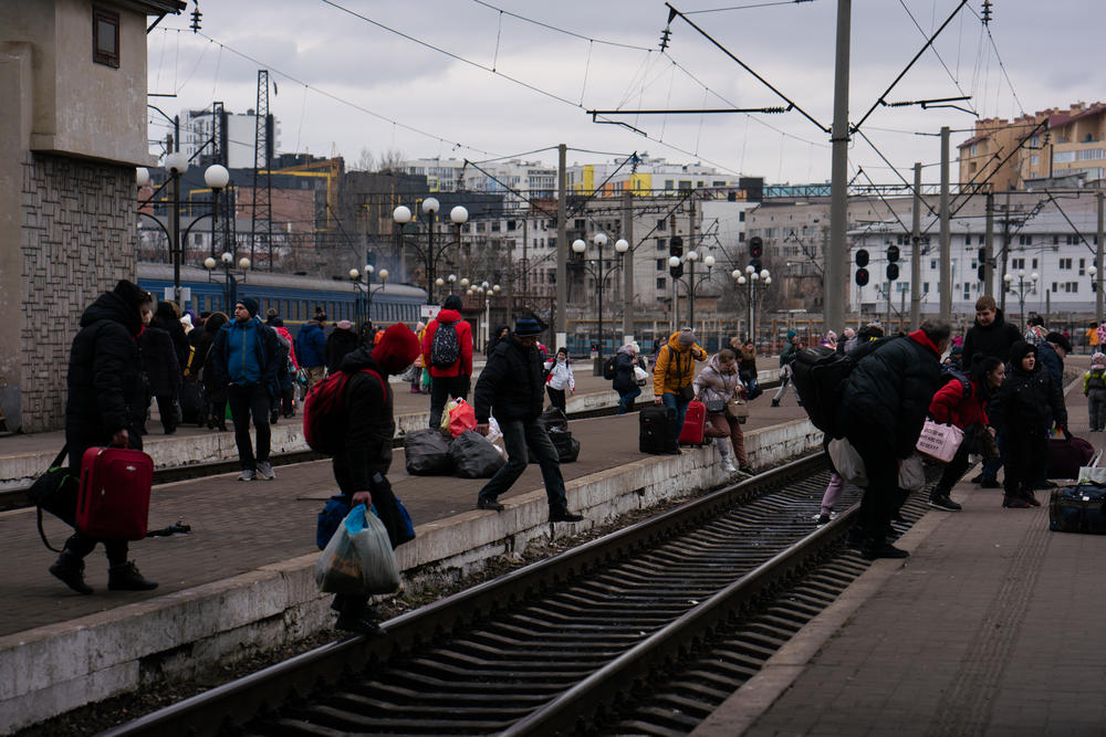 People cross the tracks at the Lviv train station. The city's mayor is calling for more international help as Lviv braces to aid even more fellow citizens.